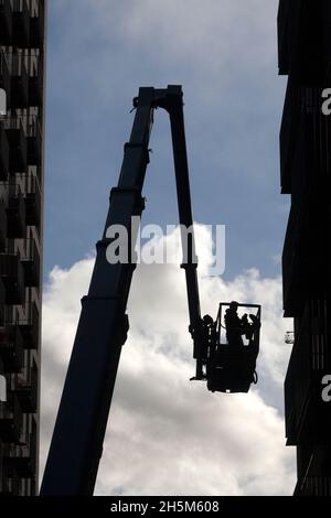 Maintenace engineer working on tower block from a crane bucket, London City Island, Leamouth Peninsula, London Stock Photo