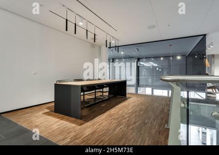 meeting table in modern office room with glass walls and thin long led lamps Stock Photo