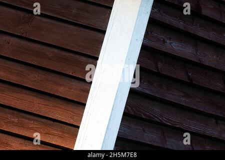 A white corner of a dark red wooden wall in Estonian countryside. Stock Photo