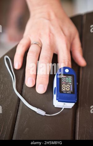 Female using oximeter for monitoring peripheral oxygen saturation, close-up view Stock Photo