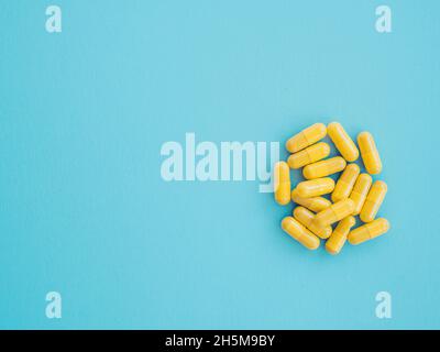 Assortment of yellow medicinal pharmaceutical products, tablets, pills, capsules on blue background. Concept of healthcare and medicine. treatment of Stock Photo