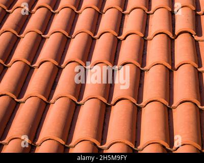 Closeup of the red clay roof tiles. Shingles. Old and used overlapping red classic style roofing material texture pattern. Spanish tiled roof Stock Photo