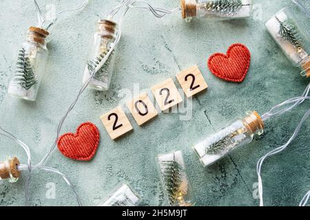 Number 2022 on wooden squares and new year decorations on a beautiful textured green background diagonally. New year and christmas concept. Top view Stock Photo