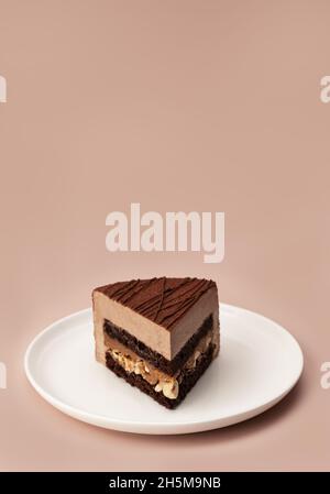 Delicious chocolate mousse cake slice with the layers and texture displayed on pastel coffee colored background. Restaurant menu and confectionery concept. Close-up. Copy space. Stock Photo
