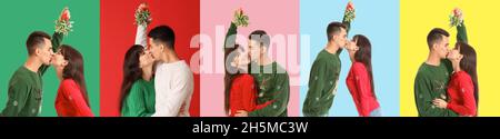 Happy young couple kissing under mistletoe branch on color background Stock Photo