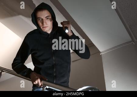 Young man with flashlight in stairway at night Stock Photo