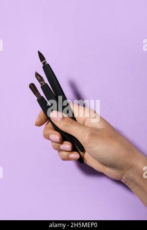 Female hand with manicure instruments on purple background Stock Photo