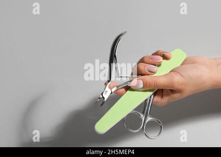 Female hand with manicure equipment on light background Stock Photo