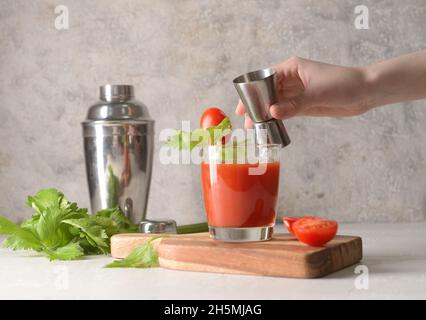 Woman making bloody mary cocktail at table Stock Photo