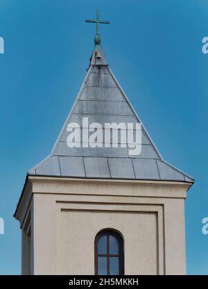 Vertical shot of a church steeple with a cross against a blue sky during the daytime Stock Photo