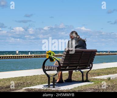 Elderly Man sitting on park bench overlooking Lake Ontario, Canada Stock Photo
