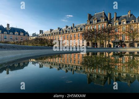 Paris, France - April 8, 2021: Nice view of Place des Vosges garden in Paris. Buildings reflected in the water of a fountain Stock Photo