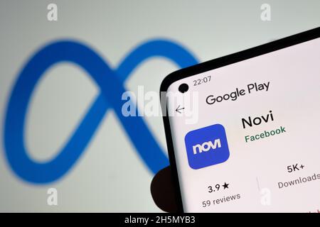 Novi app digital wallet in Google Play seen on smartphone screen, finger pointing at it and blurred FACEBOOK META logo on the background.