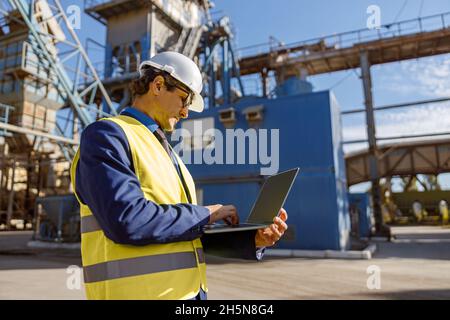 Male engineer working on notebook outdoors at factory Stock Photo