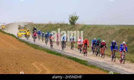 Viesly, France - April 14, 2019: The peloton riding on the dusty cobblestone road from Briastre to Viesly during Paris Roubaix 2019. Stock Photo