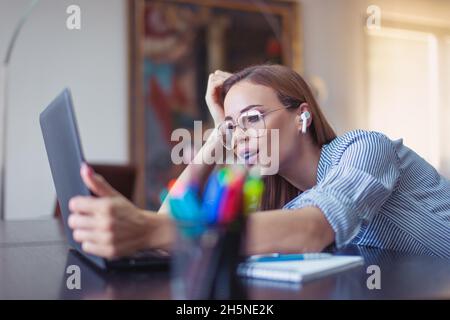 Young businesswoman wondering on financial result in home office, using laptop and hands free device Stock Photo