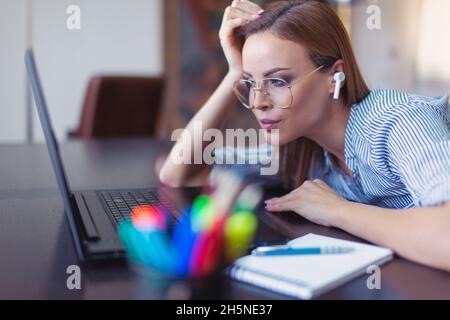 Young nerd Caucasian businesswoman focusing on work at home office Stock Photo