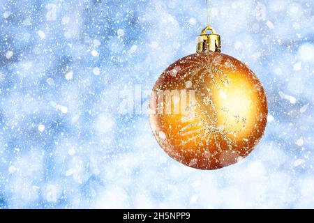 Golden Christmas ball in the snow on a blurred blue-gray background. Copy space. New year greeting card Stock Photo