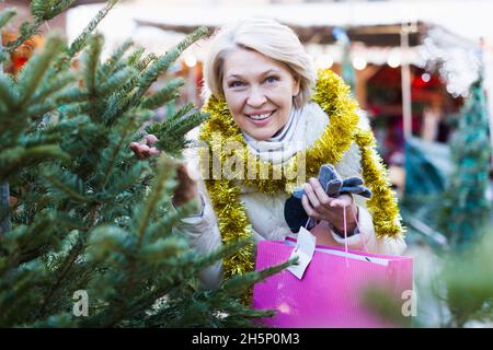 Adult woman is choosing Christmas tree in the market Stock Photo