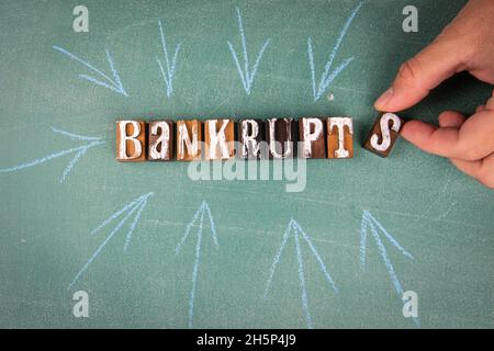 Bankrupts. Text with arrows on a green chalk board. Stock Photo