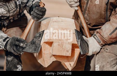 Closeup Two Carpenter with axe working with log wooden. Woodwork job, house frame building. Stock Photo