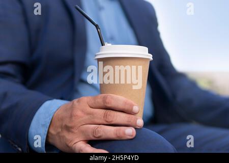Handsome businessman enjoying on pause and drinking coffee to go. paper cup of coffee in a man's hand close-up Stock Photo
