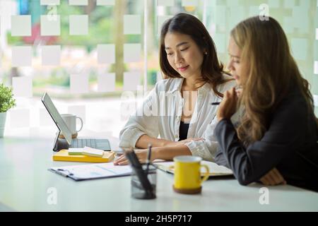 Two professional female business workers are brainstorming and discussing a new business model and marketing strategy. Stock Photo