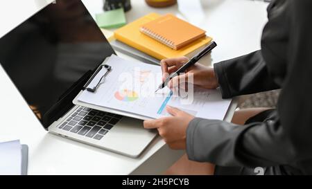 Cropped image of female executive checking financial statement on the data chart report at her desk. Stock Photo