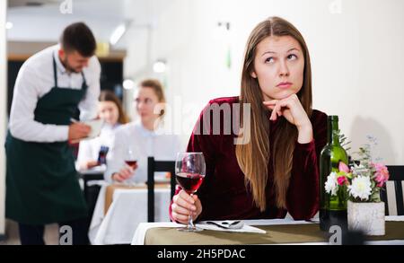 Sad woman is dining in luxury restaurante alone Stock Photo