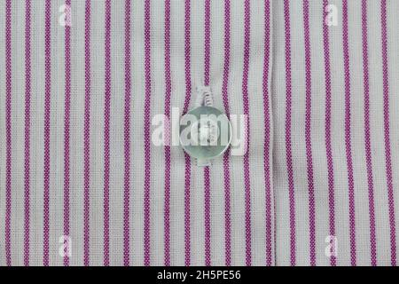 Close-up of white button on striped red and white shirt pattern Stock Photo