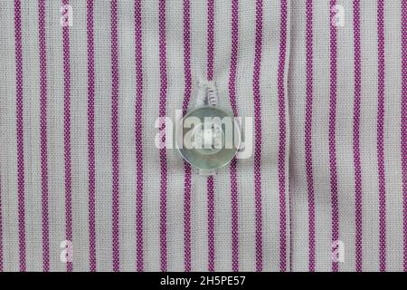Close-up of white button on striped red and white shirt pattern Stock Photo
