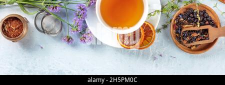 Tea panorama with a place for text, with a tea strainer, flowers, and herbs, shot from the top Stock Photo