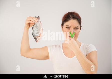 Caucasian woman with a clothespin on her nose because of the disgusting smell of fish. A metaphor for women's health and intimate hygiene. Stock Photo