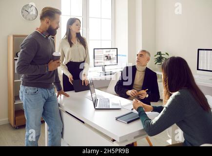 Group of staff in office discusses work issues and new ideas during informal meeting. Stock Photo