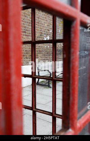 Bench seen through a telephone box on Waller Road, New Cross, London, UK Stock Photo