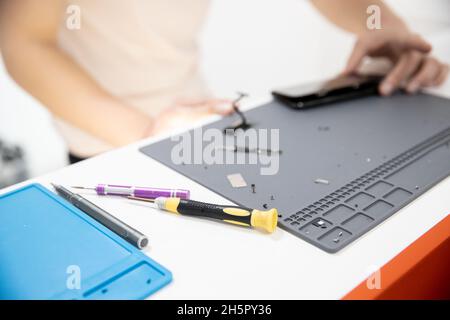 Master disassembles modern mobile phone, repairs and replaces battery, broken screen. Stock Photo