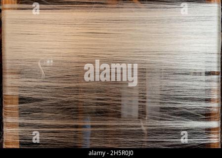 Thin white woven threads on weaver loom in folk museum Stock Photo