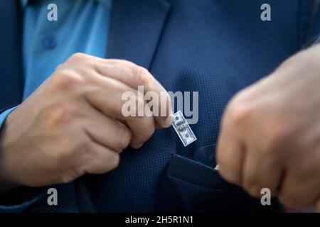 young businessman guy holds a small bill in his hand as a symbol of declining income. Small salary concept. The businessman will put a small bill in h Stock Photo