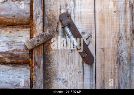 Iron handle on a wooden wall. The door is closed with a wooden catch. Stock Photo
