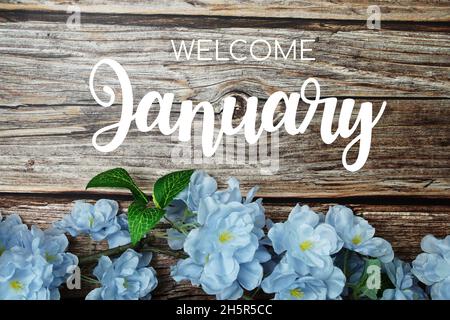 Welcome January typography text with blue flowers on wooden background Stock Photo
