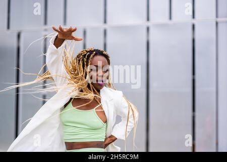 Photo with selective focus of an african woman dancing with energetic movements in a urban landscape Stock Photo