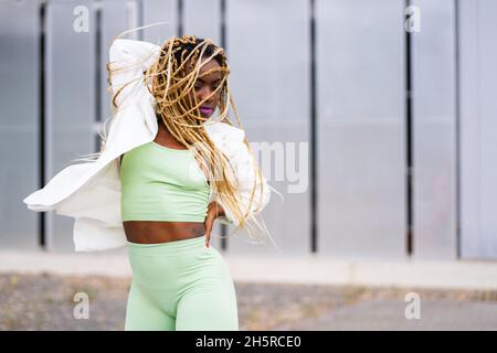 Photo with motion of an afro woman with braids dancing with energetic movements in a urban landscape Stock Photo
