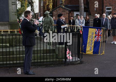 Syston, Leicestershire, UK. 11th November 2021. The last post is played near a life size knitted soldier during Armistice Day commemorations at the Syston War Memorial. Credit Darren Staples/Alamy Live News. Stock Photo