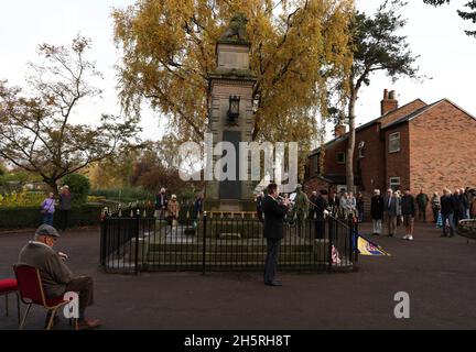 Syston, Leicestershire, UK. 11th November 2021. The last post is played near a life size knitted soldier during Armistice Day commemorations at the Syston War Memorial. Credit Darren Staples/Alamy Live News. Stock Photo