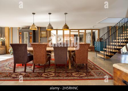 Suffolk, England - March 2018: Dining hall within converted barn dominated by a large dining table with eight chairs Stock Photo