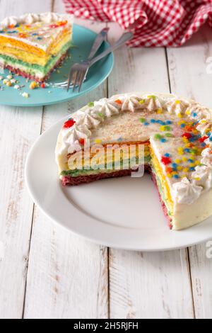 Rainbow layer cake on white wooden table Stock Photo