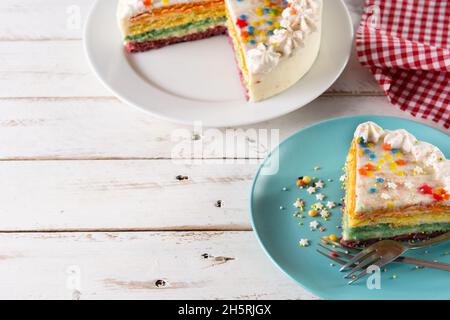 Rainbow layer cake on white wooden table Stock Photo