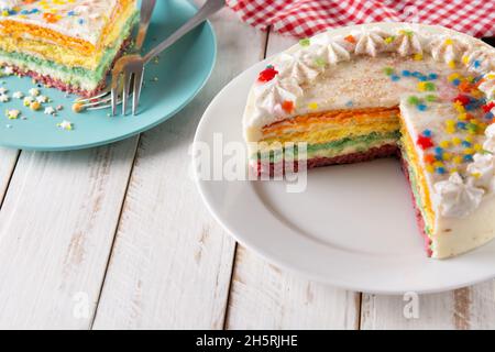 Rainbow layer cake on white wooden table Stock Photo
