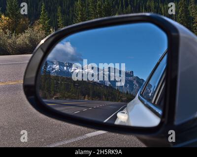 Stunning view of Yellowhead Highway in Jasper National Park, Alberta, Canada through the side mirror of a white car with forest and the Rockies. Stock Photo