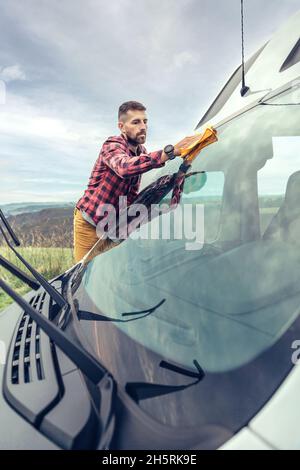 Man cleaning camper van windshield outdoor Stock Photo